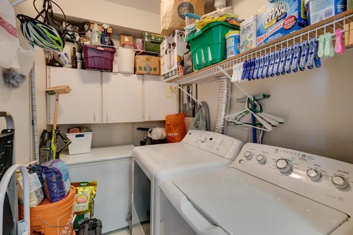 Clothes washing area featuring cabinet space and washing machine and dryer and storage space