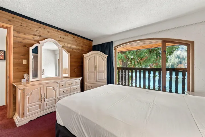 Wood-paneled accent wall, red carpeting, and a large arched window with a wood frame