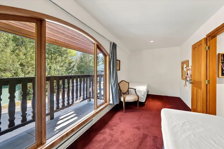 Arched wood-frame window with sliding door access to an exterior balcony featuring a turned wood railing