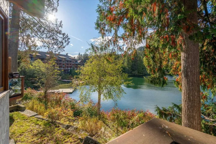 Lakefront property with mature trees, natural rock landscaping, and deck