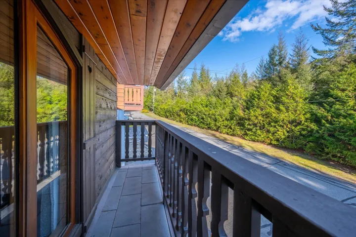 Private balcony with stone tile flooring, a wooden ceiling, and a carved wood railing