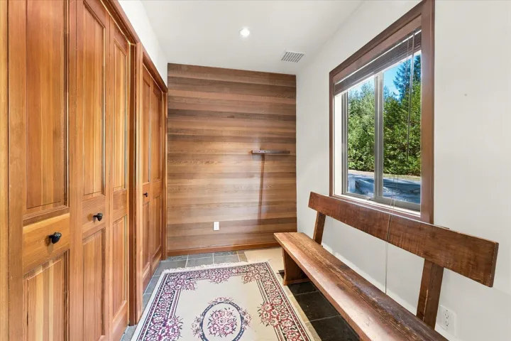 Built-in wood cabinetry with black hardware, wood plank accent wall, recessed lighting, and a large window with wood trim