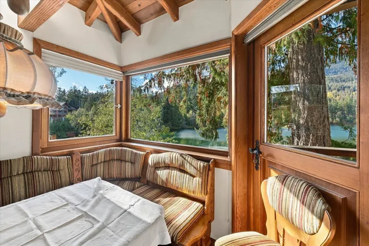 Corner banquette seating with wood-finish framing, large windows, and exposed wood ceiling beams