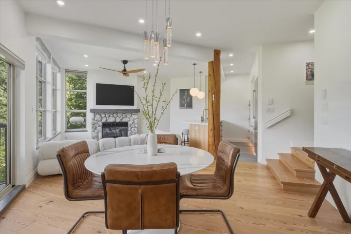 Open-concept living space featuring wood-finish flooring, a stone-clad fireplace, and recessed lighting