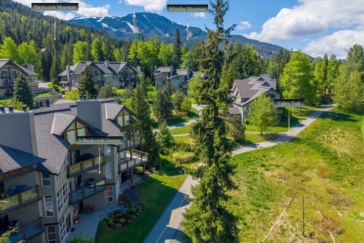 Modern multi-story residential building with multiple balconies, pitched shingle roof, and dormer windows