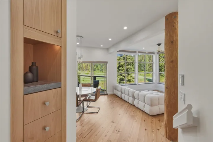 Built-in wood cabinetry with a recessed display niche, wood-finish flooring, vaulted ceiling with recessed lighting, and a prominent wood support column