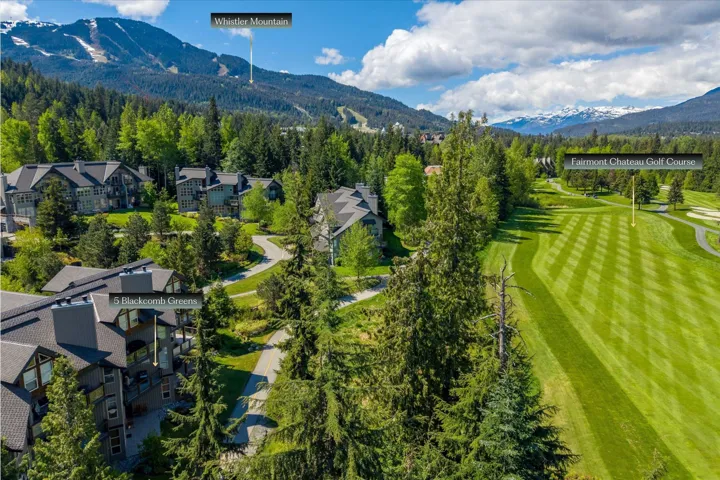Mountain setting featuring a golf course, mature trees, and residential buildings with dark-pitched roofs