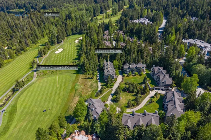 Aerial perspective showcasing a golf course, forested areas, and a body of water
