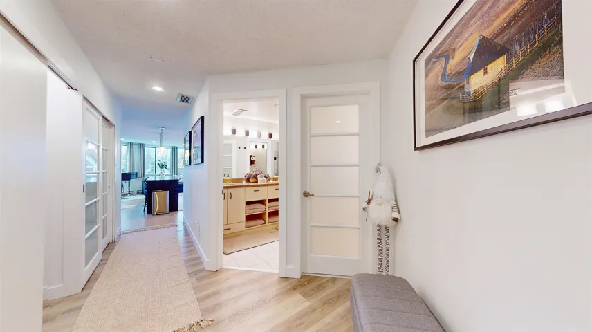 Corridor featuring light wood-style flooring, recessed lighting, and a textured ceiling