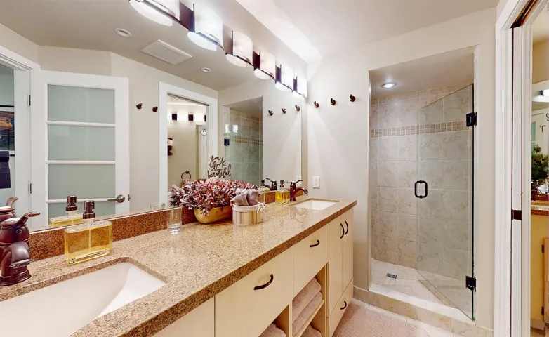 Full bathroom with double vanity and a stall shower