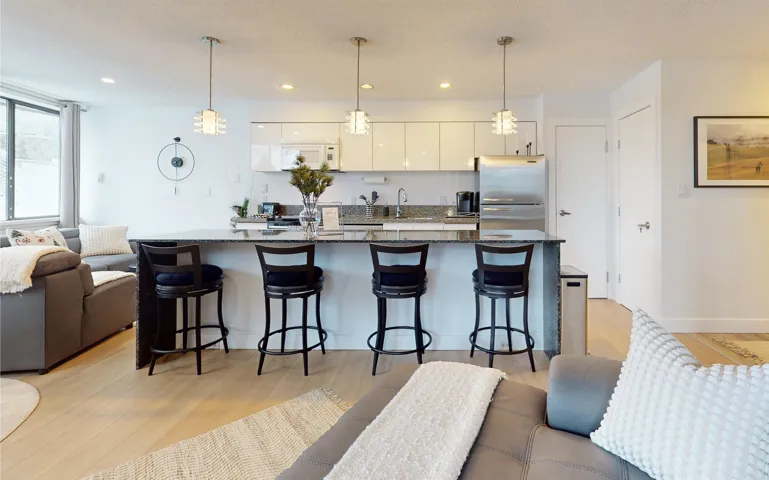 Kitchen with open floor plan, light wood finished floors, a breakfast bar, pendant lighting, and freestanding refrigerator