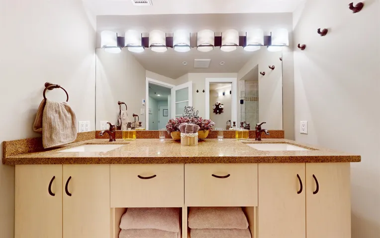 Full bathroom featuring double vanity and tiled shower