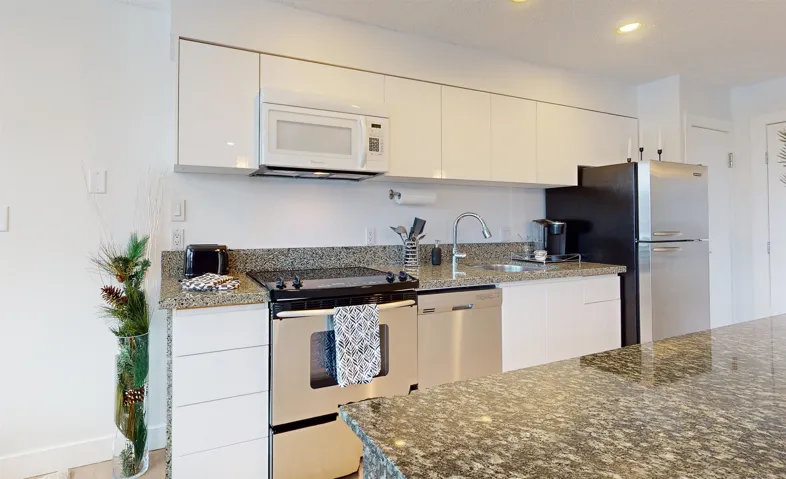 Kitchen featuring stainless steel appliances, dark stone countertops, white cabinets, modern cabinets, and recessed lighting
