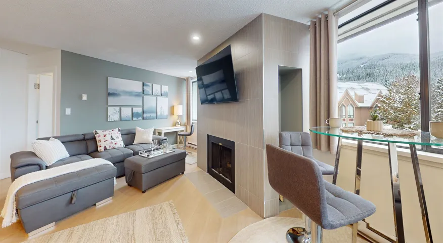 Living room with a large fireplace, recessed lighting, a textured ceiling, and light wood-type flooring