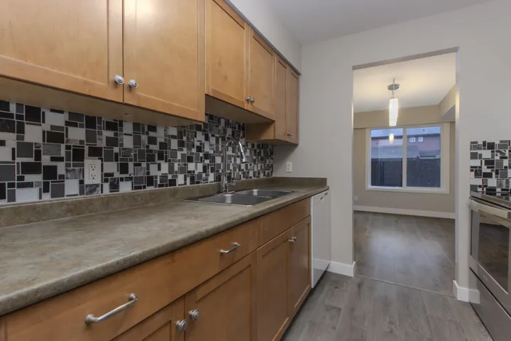 Kitchen with tasteful backsplash, dark wood-type flooring, stainless steel electric range, and dishwasher