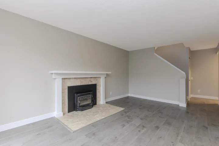 Unfurnished living room featuring light wood finished floors and a wood stove