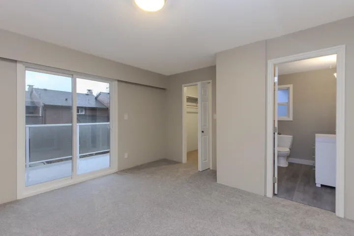Unfurnished bedroom with a walk in closet, light carpet, access to outside, and ensuite bath