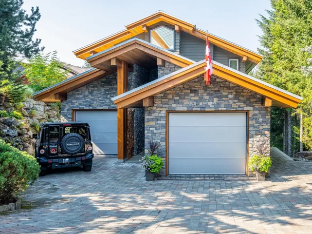View of front of property featuring stone siding, a garage, and decorative driveway