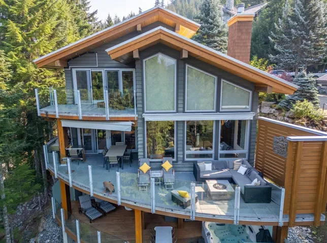 Rear view of house featuring a wooden deck, an outdoor living space with a fire pit, a chimney, and outdoor dining area