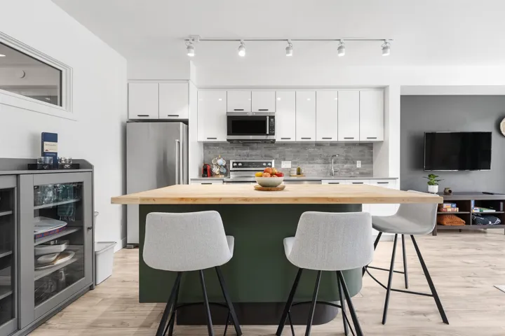 Kitchen with a breakfast bar area, butcher block counters, white cabinets, a kitchen island, and stainless steel appliances