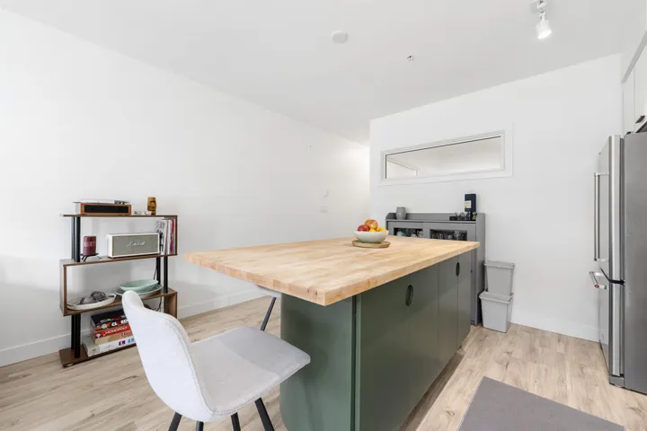 Kitchen featuring wood counters, freestanding refrigerator, a kitchen breakfast bar, light wood-type flooring, and a center island