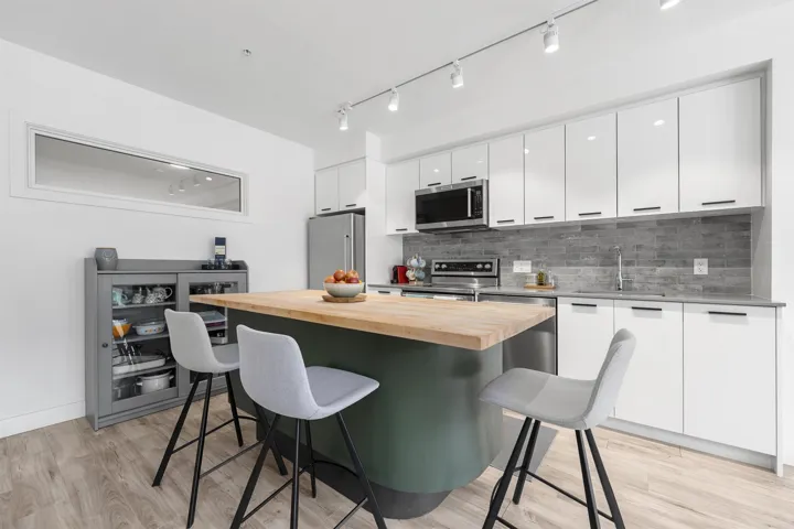 Kitchen with white cabinets, butcher block counters, light wood finished floors, a kitchen bar, and track lighting