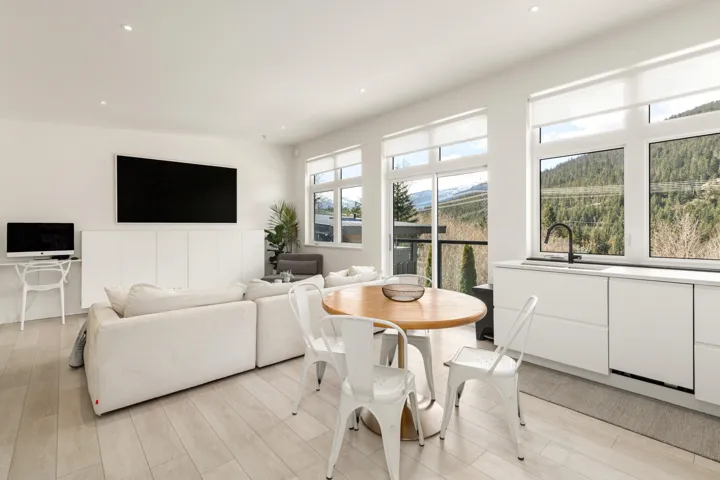 Open-concept living space featuring wood-finish flooring, recessed lighting, expansive windows, built-in cabinetry, and a modern kitchen with a black faucet