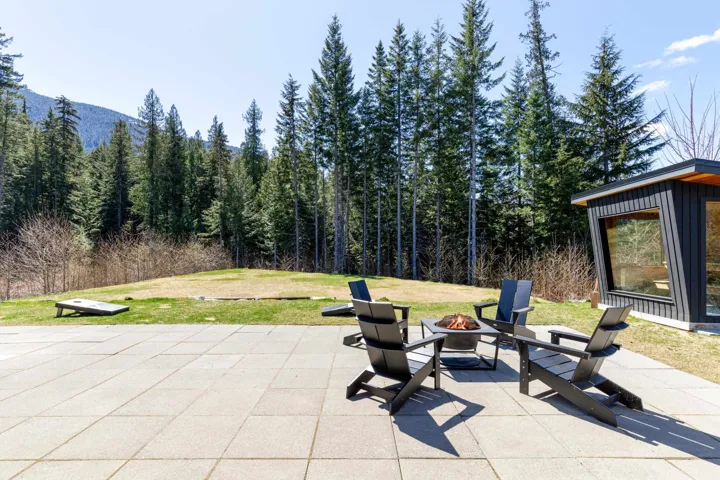 Expansive paver patio featuring a central fire pit, bordered by a substantial grassy area