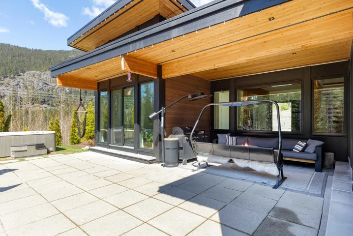 Exterior patio featuring large format pavers, a hot tub, and a covered section with wood-finish ceiling