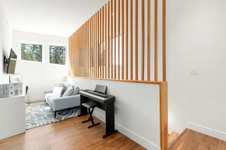 Open-concept living space featuring wood-finish flooring, a contemporary wood slat wall, and white trim