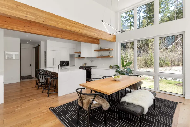 Open-concept living space featuring a double-height ceiling, exposed wood beams, and wood-finish flooring