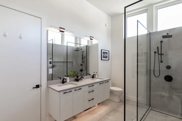 Modern bathroom featuring a dual vanity with light countertops, black fixtures, and under-cabinet storage