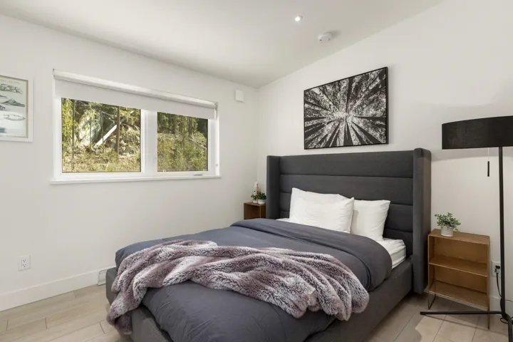 Bedroom with contemporary light wood-finish flooring and bright white walls