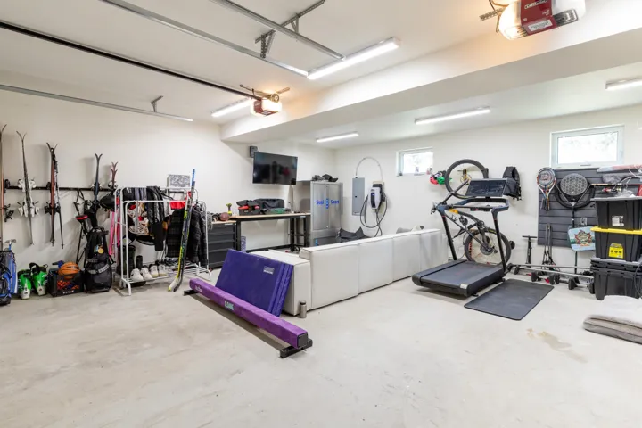 Spacious garage featuring concrete flooring and exposed ceiling beams
