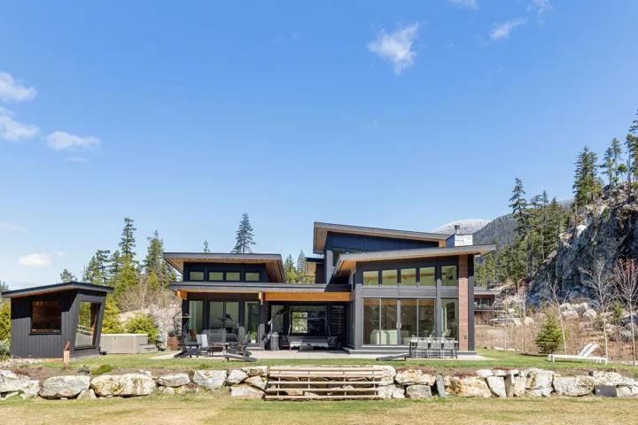 Modern architectural residence with expansive glass walls, a multi-level roofline, and an outdoor patio area