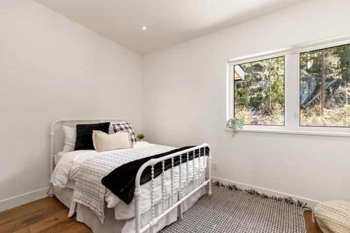 Room featuring wood-finish flooring, white walls, recessed lighting, and a large window