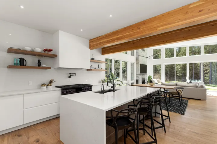 Gourmet kitchen featuring a white countertop island with seating, a professional-grade range with a pot filler, and open wood shelving