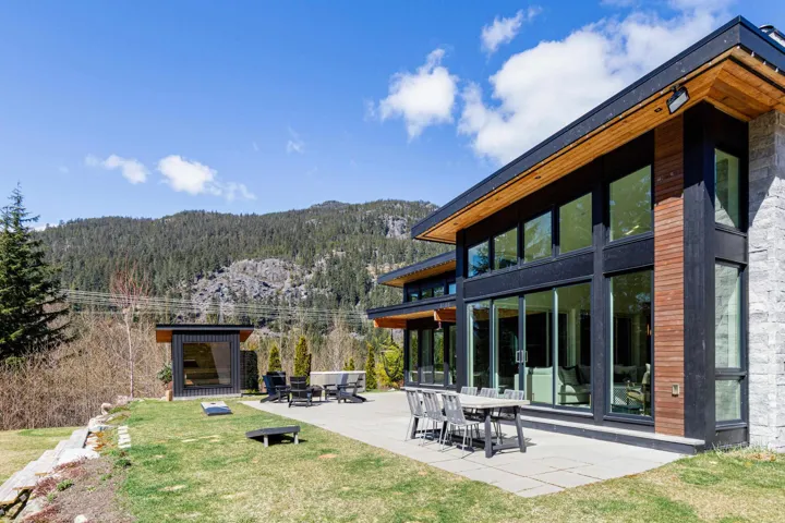 Expansive outdoor patio with stone-finish pavers, multiple seating areas, and a detached outbuilding