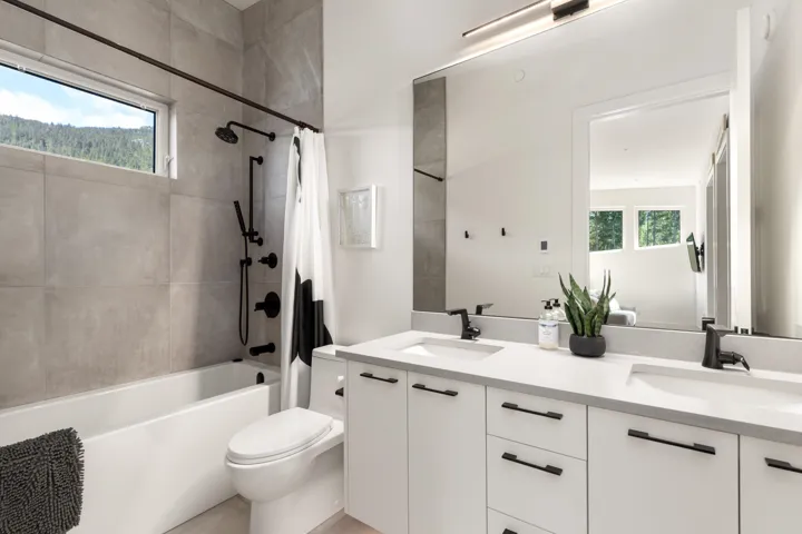 Bathroom featuring a dual vanity with light countertops, black hardware, and integrated sinks
