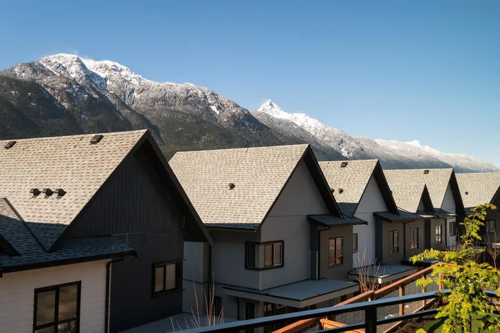 Row of modern townhomes with pitched roofs and dark siding