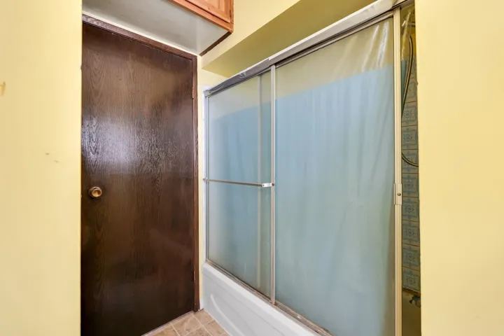 Bathtub with sliding opaque shower doors and patterned tile surround