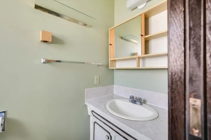 Bathroom vanity featuring a drop-in sink with a dual-handle faucet