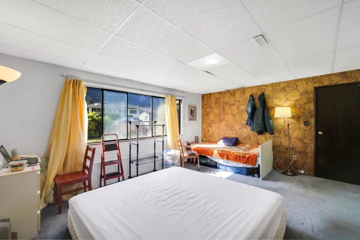 Expansive room featuring a dropped ceiling with recessed lighting, full-wall windows, and textured accent wall