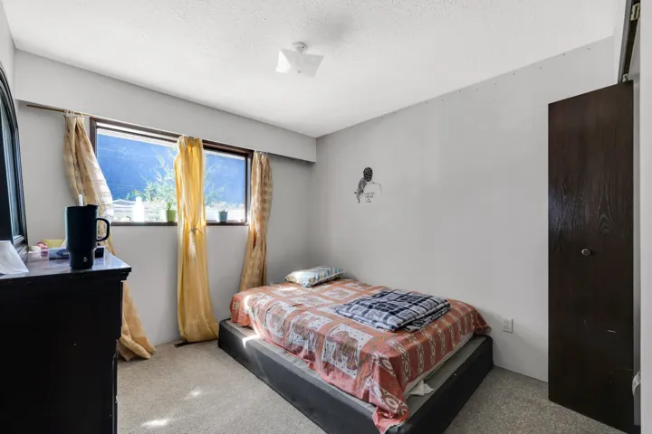 Bedroom featuring two large windows with natural light, wall-to-wall carpeting, and a dark wood-finish sliding door