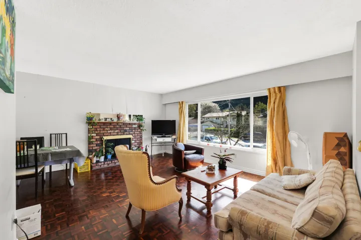 Living area featuring wood-finish parquet flooring, a brick-surround fireplace, and a large picture window