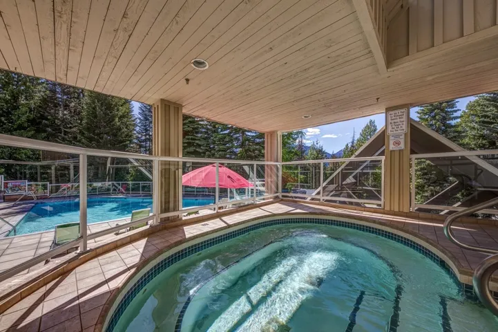 Covered outdoor hot tub with tiled surround and metal handrails