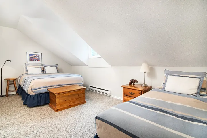 Bedroom with a baseboard heating unit, vaulted ceiling, carpet floors, and a textured ceiling