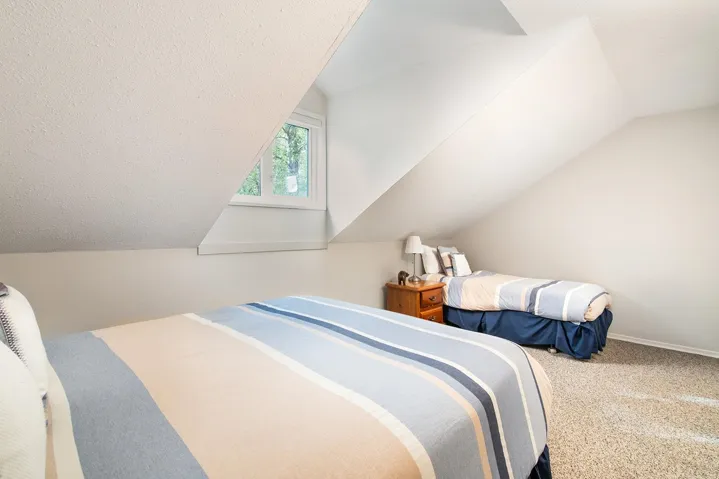 Carpeted bedroom with lofted ceiling and baseboards