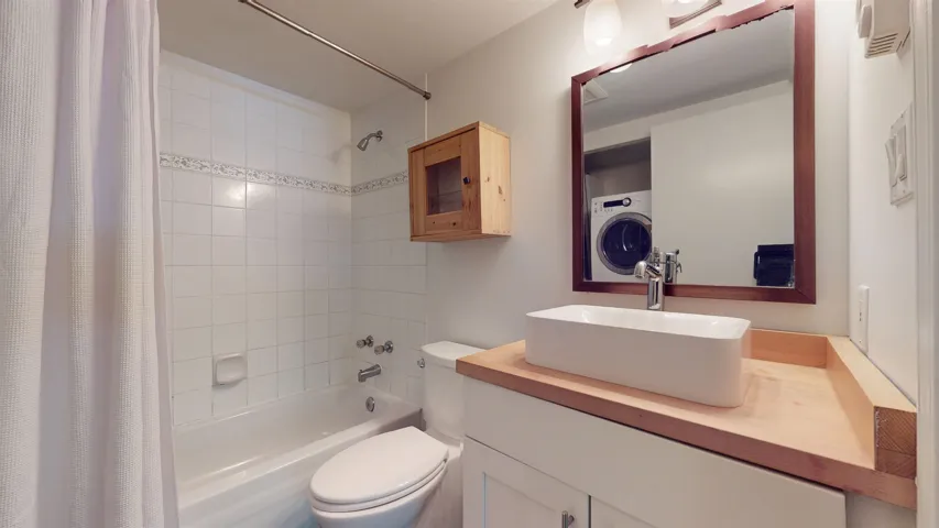 Bathroom with shower / tub combo with curtain, vanity, and washer / clothes dryer