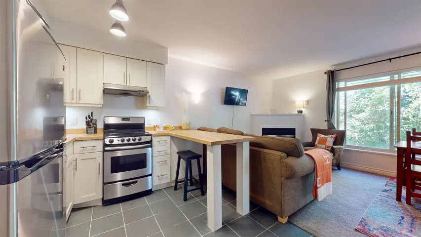 Kitchen featuring stainless steel appliances, open floor plan, white cabinets, a peninsula, and dark tile patterned floors